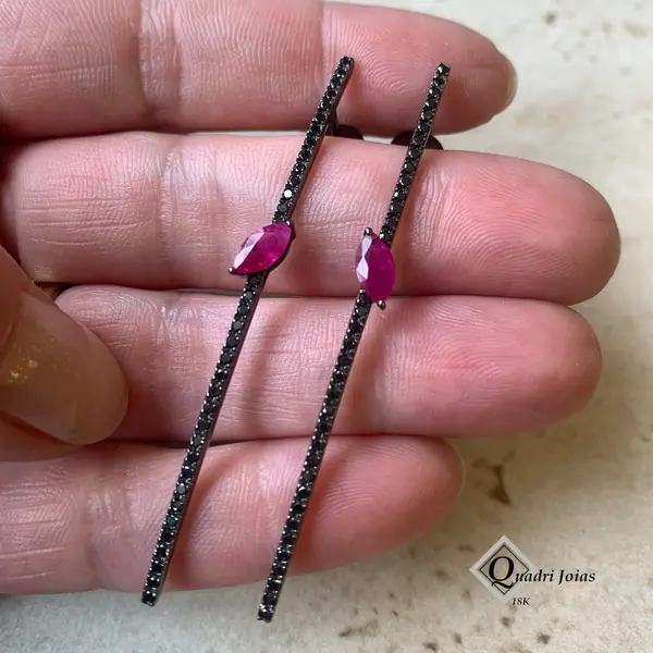 Brincos de rubi e diamantes negros na palma da mão